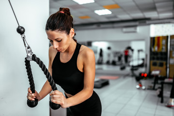 Exercising with cable weight machine in gym.