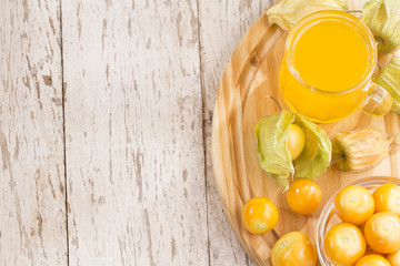 Poster - Uchuva juice. Wooden background - Physalis peruviana