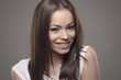 © sharplaninac - Charming beautiful young brunette woman smiling and looking at camera. Close up portrait over gray studio background.