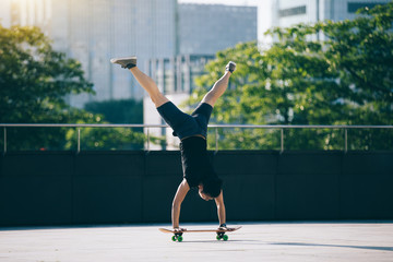 Wall Mural - Skateboarder practice handstand on skateboad at city