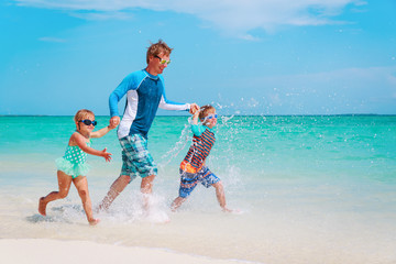 father with kids play with water run on beach