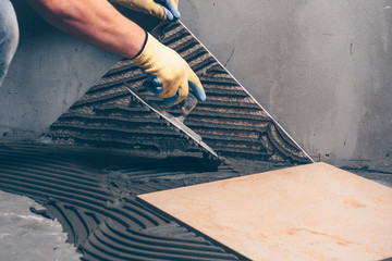 Working tiles correct the level of glue under the tile on the floor