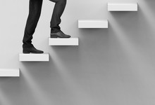 3d Rendering. A Business Man Climbing Up On Staircase With Copy Space Wall Background.