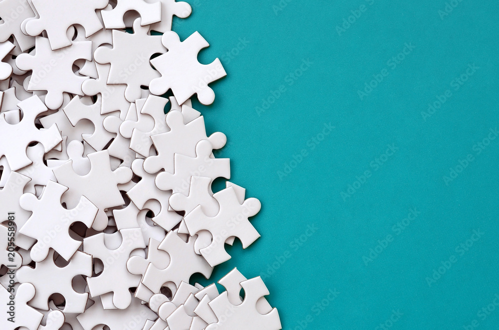 A pile of uncombed elements of a white jigsaw puzzle lies on the background of a blue surface. Texture photo with copy space for text - obrazy, fototapety, plakaty 