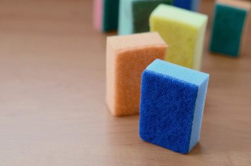 A few kitchen sponges lie on a wooden kitchen countertop. Colorful objects for washing dishes and cleaning in the house are ready for use