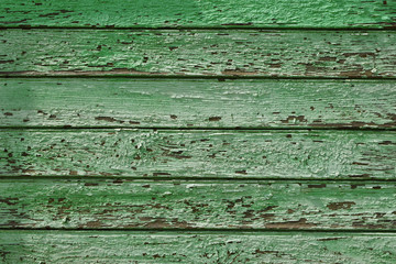 Green planks with cracked paint of outdoor wall of old wooden facade house as abstract background.