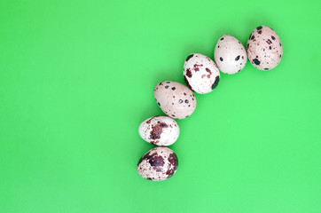 Quail eggs on a light green surface, top view, empty place for t