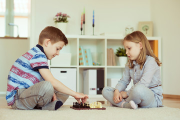 Wall Mural - Two little children playing chess at home