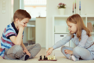 Wall Mural - Portrait of two little children concentrated playing chess