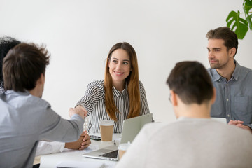 Wall Mural - smiling businesswoman shaking hand of male partner at negotiations, friendly woman handshaking man g