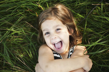 High Angle Portrait Of Happy Girl Lying On Grassy Field At Park