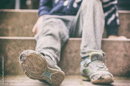 Fotografía Alte kaputte Schuhe eines kleinen Jungen als Symbol für Kinderarmut