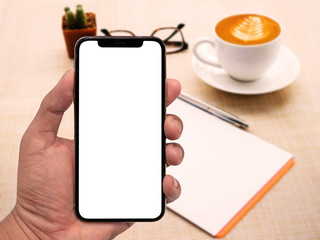 Poster - Hand using smartphone white screen with workspace on wood table.