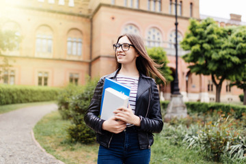 New study year begin. Female student holding notebooks outdoors and smiling on Uni background