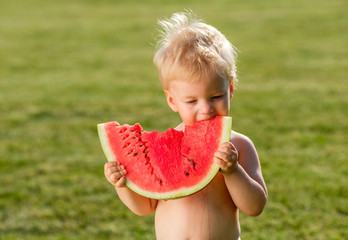 Wall Mural - One year old baby boy eating watermelon in the garden