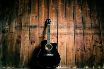 Acoustic guitar on a wooden texture with copy space for a text. Music and leisure concept. Guitar against wooden wall.