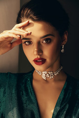woman with dark hair and perfect glowing skin, in elegant dress and jewelry