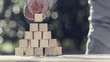 Retro toned image of man building a pyramid with blank wooden blocks outdoors