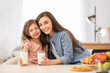 © New Africa - Mother and daughter having breakfast with milk at table