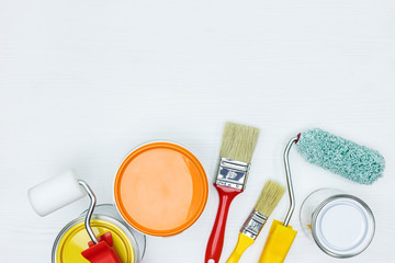 Poster - cans with white, orange and yellow paint, brushes, rollers on white wooden surface flat view