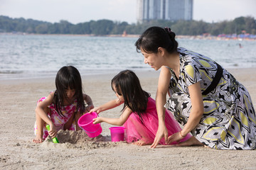 Wall Mural - Asian Chinese mum and daughters playing sand together