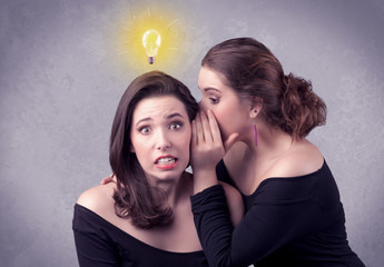 Wall Mural - A young girl has an idea illustrated with a drawn glowing light bulb above the head, while a friend whispers a secret in her ear concept.