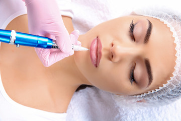 Young woman getting permanent makeup on lips in beautician salon, closeup