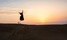 Silhouette Of A Woman Jumping In The Desert