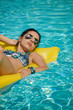 © ZoomTeam - Woman relaxing on donut lilo in the pool at private villa. Inflatable mattress. Summer holiday idyllic.