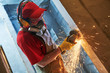 © Kadmy - home renovation. worker cutting metal reinforcement rods in doorway by grinder