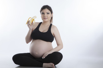 Healthy pregnant woman eating vitamin rich fruit over white background