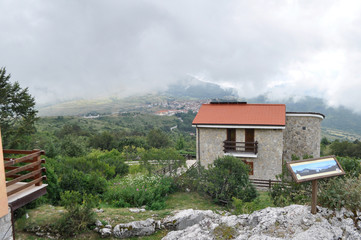 house andmountains high in the clouds, covered with trees