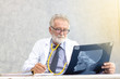 © thbangkok - Senior medical doctor or chief doctor or Surgeon are checking skull of human head via x-ray film In examination room with copy space.