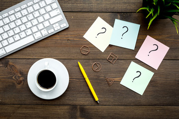 Poster - Question mark on sticky notes on office desk on dark wooden background top view. FAQ concept. Working with clients. Troubles in work.