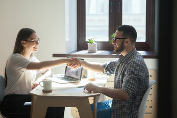 Wall Mural - Smiling female employer shaking hand of male job applicant after successful closing business deal, greeting with new work position. Concept of cooperation, first impression, recruitment, employment