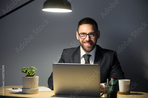 Happy Ceo Smiling At Camera While Working At Laptop Late At Night