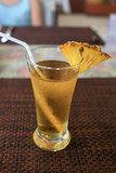 Fototapeta  - Pineapple juice in a glass with drinking straw and a piece of pineapple.