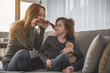 © Yakobchuk Olena - Best friends. Full length portrait of high-spirited, energized woman with her small daughter playing on sofa. Mother is putting her child curls to her face as if moustache