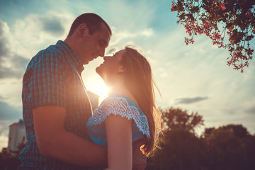 Couple in love hugging and smiling in spring park at sunset.