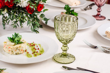 Empty green glass on white tablecloth in a restaurant banquet, background with snacks and glasses of wine, close up. Concept: Furshet. Serving. Celebration. Anniversary. Wedding