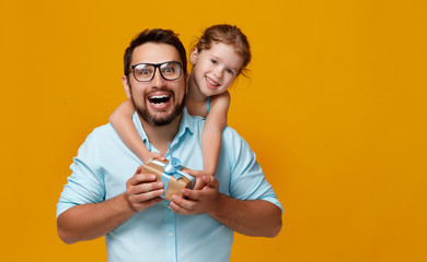 happy father's day! cute dad and daughter hugging on yellow background.