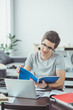 © LIGHTFIELD STUDIOS - male student doing homework with copybooks and laptop at home
