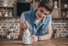 Handsome Teenager Taking Dollar Banknotes From Saving Glass Jar For Money