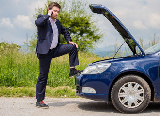 Wall Mural - A broken car on the road, a man talks to a cell phone and calls for help on the road