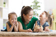 © Oksana Kuzmina - kids and their mother reading a book on floor in cozy living room