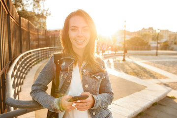 Wall Mural - Happy woman outdoors using mobile phone