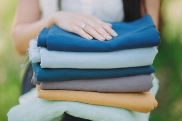 cropped image of smiling seamstress holding stack of colored fabric