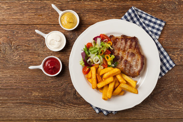 Grilled pork neck served with French fries and salad.