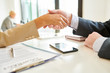© Seventyfour - Side view close up of unrecognizable female manager shaking hands with client over contract lying on table after negotiations during meeting in office