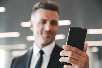 smiling mature businessman looking at mobile phone